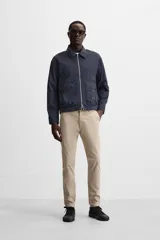 Pantalón chino azul marino, corte skinny fit, confeccionado en tejido de algodón con elasticidad. Cuenta con bolsillos frontales y traseros de vivo. Cierre frontal con cremallera y botón.