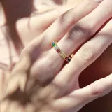 Anillo dorado con cristales redondos multicolores, diseño delicado y elegante.
