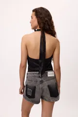 Top amarillo de satén con cuello halter y flecos negros.