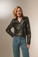 Chaqueta corta de eco cuero negra con tachas plateadas, cuello camisero y cierre frontal con cremallera.
