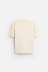 Polo color crema de punto, corte regular fit, cuello solapa con abertura frontal y manga corta.