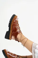 Sandalias de cuero color marrón con textura de cocodrilo, plataforma con suela track y tiras finas que se atan al tobillo.