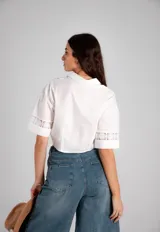 Camisa blanca de manga corta con detalles de broderie y nudo para atar en la parte delantera.
