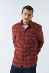 Sobrecamisa de algodón para hombre con interior de corderito, estampado a cuadros en tonos negro, blanco y azul. Tiene cierre de botones, bolsillos tipo cartera y logo en goma. El modelo usa talle M.