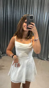 Vestido corto blanco con brillos plateados, escote drapeado y breteles finos.