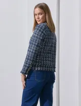 Chaqueta tipo blazer en tejido tweed azul con detalles en blanco y lurex. Tiene escote mao, abertura central, bolsillos delanteros y puños con aplique de botones perlados. Terminación desflecada y forro interno.
