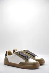 Zapatillas urbanas de cuero ecológico blanco con puntera y talón de gamuza sintética color beige. Cordones negros y suela de goma color caramelo.