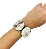 Pulsera elástica con piezas circulares de resina color blanco con manchas marrones y engarce negro.