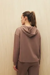 Canguro marrón con capucha, corte amplio y detalle de recorte frontal.