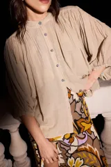 Camisa beige de algodón con mangas murciélago y botones rayados.