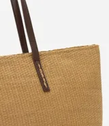 Bolso de playa mediano de fibra de papel color marrón claro, con asas de hombro pespunteadas en marrón oscuro. Incluye un neceser con cierre.