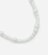 Collar corto de perlas artificiales blancas de diferentes tamaños, con cierre de gancho.