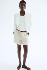 Short color crema de lino y viscosa, con cintura elástica ajustable con cordón, bolsillos laterales y aberturas laterales en el ruedo.