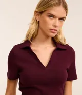 Blusa color blanco con cuello polo y escote en V, de manga corta y corte ajustado.