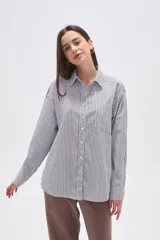 Camisa de algodón holgada con cuello camisa, botones frontales y estampado de rayas verticales finas en blanco, negro y rosado.