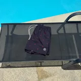 Short de baño negro con estampado de siluetas rojas, cintura elástica con cordón blanco y logo de la marca en la pierna.