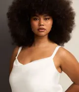 Blusa de satén color blanco, con escote drapeado y breteles finos ajustables. El bajo es irregular.