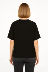 Remera negra de poliéster, manga corta, corte holgado y cuello redondo.
