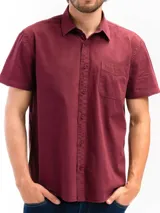 Camisa de manga corta color beige, confeccionada en 100% algodón, con cuello clásico, cierre frontal con botones y bolsillo en el pecho.