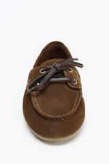 Zapato náutico color marrón de serraje con detalle de pespuntes en el cuerpo y pasados en los laterales. Cierre mediante cordones y suela efecto engomado.