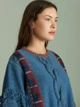 Sweater negro oversize de lana con cuello redondo, bordado central en forma de trenza, laterales con cuadrillé y mangas acampanadas desflecadas.