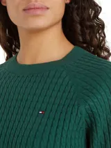 Sweater verde de punto trenzado de algodón orgánico, con cuello redondo y corte amplio. Presenta el logo de Tommy Hilfiger bordado en el pecho.