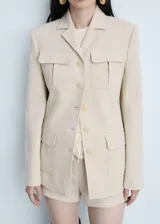 Chaqueta beige de corte estructurado, con cuatro bolsillos frontales y botones al tono.