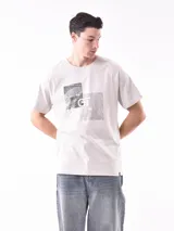 Remera manga corta color gris claro con estampado de dos rectángulos con diseño de hojas y letras en color gris oscuro.