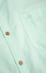 Camisa amarilla de algodón orgánico, manga larga con botones de madera, cuello italiano, calce regular, bolsillo de pecho con logo bordado.