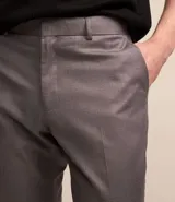 Pantalón de vestir gris, de corte slim fit, con bolsillos laterales y traseros. Se ajusta a la cintura con cinturón de cuero negro.