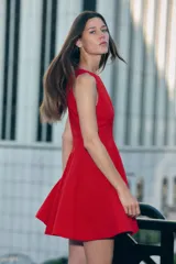 Vestido corto sin mangas color rojo, con escote redondo y falda con vuelo. Presenta costuras moldeadoras en la parte delantera y trasera, y cierre oculto en la espalda.