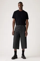 Pantalón capri de denim negro con corte amplio, tiro alto y cinturón de tela con hebilla metálica.