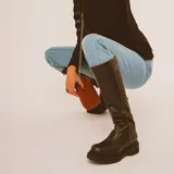 Botas de caña alta color beige y puntera marrón, con suela track y detalle de estrella blanca en el lateral.