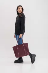 Bolso shopper color bordó con tachas plateadas y bolsillo interno.
