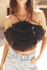 Top negro de organza con cuello halter, tirantes finos y detalle de maxi flor con volumen.