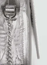 Bolso pequeño plateado con efecto piel y textura. Tiene bandolera y cierre de solapa con botón magnético.