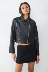 Campera biker negra de efecto cuero, con cierre delantero asimétrico, bolsillos laterales con cierre y cuello con solapa adornado con tachas.