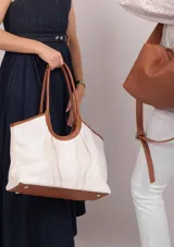 Bolso tipo tote de cuero y gamuza azul con diseño de ondas blancas. Tiene doble asa de cuero azul y base de cuero graneado. El exterior es de gamuza y tela 100% algodón.