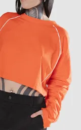 Remera corta naranja con mangas cortas abullonadas y ribete blanco en cuello, mangas y laterales.