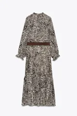 Vestido midi con estampado animal cebra en tonos blanco y negro, cuello redondo con lazada ajustable, manga larga con puños elásticos, forro interior y cinturón marrón con hebilla metálica.