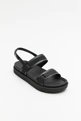 Sandalia negra con base chunky de goma liviana, tiras de material sintético ajustables y hebilla metálica.