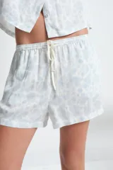 Conjunto de pijama de viscosa color blanco con estampado floral celeste, compuesto por una camisa de manga corta con cuello y botones, y un short con cintura elástica.