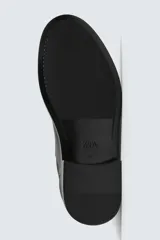 Bota corta estilo Chelsea de cuero liso negro, con elásticos laterales y tirador trasero para calce. Presenta horma redonda y suela con ligero tacón.