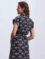 Vestido corto estampado blanco y negro, marca Luxology. Escote en V cruzado con solapa, cintura elastizada con pasadores y lazo de ajuste, y manga corta.