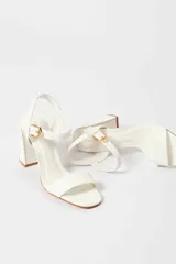 Sandalias de tacón alto color lila, con tira delantera y tobillera con hebilla dorada.