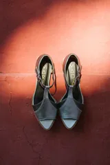 Sandalias de cuero color blanco con detalles dorados, taco bajo de madera y tira con hebilla al tobillo.