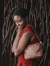 Bolso bandolera pequeño de cuero vacuno lavado color negro, con tachas metálicas doradas y plateadas en la parte frontal y en la correa. Tiene cierre con cremallera, asa de hombro extraíble, bandolera regulable y extraíble, bolsillos internos y forro de algodón. Incluye un colgante con el logo de la marca.