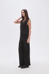 Pantalón ancho de poliéster negro con rayas verticales blancas, de calce medio y bolsillos laterales.