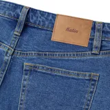 Pantalón de jean azul oscuro, de corte recto, con cinco bolsillos y calce amplio en muslo y rodilla.