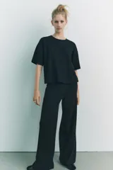 Pantalón negro de pierna ancha confeccionado en tejido de punto canalé con algodón. Tiene tiro medio y cintura con elástico interior.
